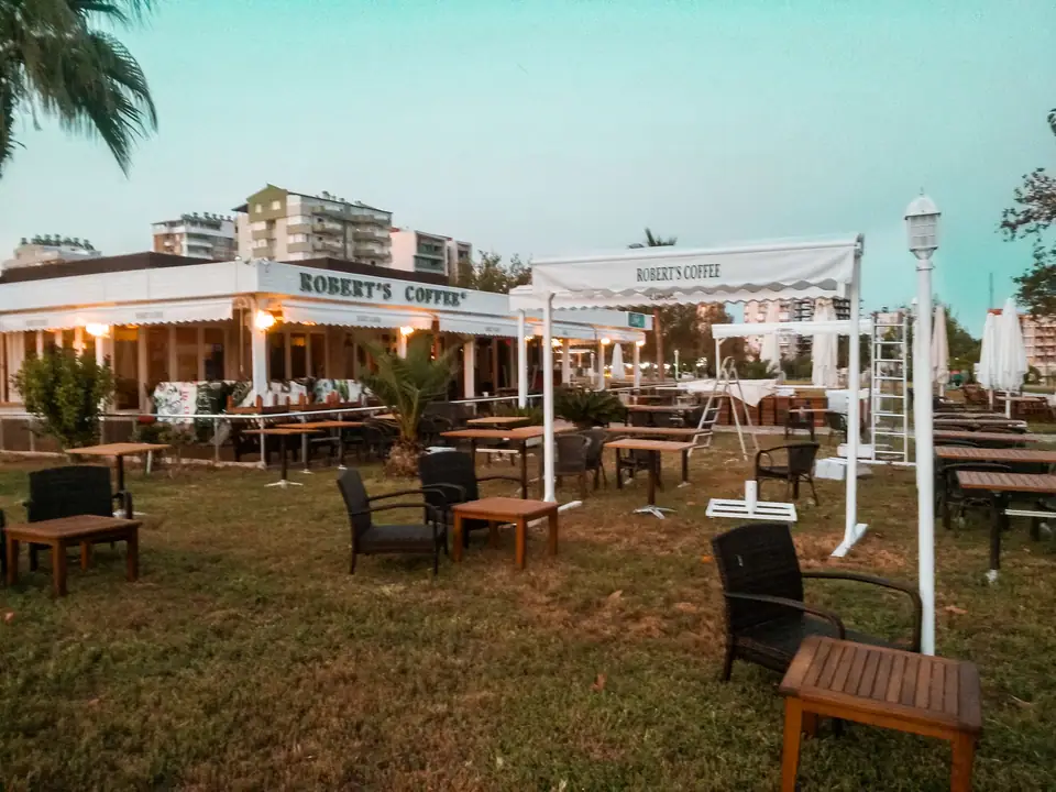 Kafe bahçesinde direkli beyaz mafsallı tente